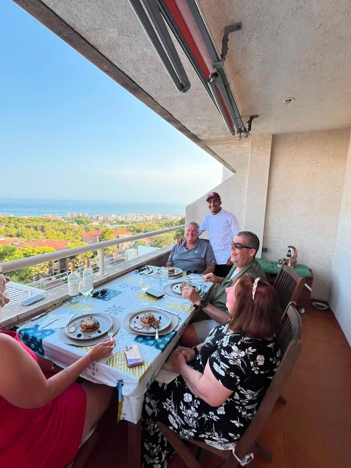 Moneim con los invitados de una cena privada en una terraza frente al mar