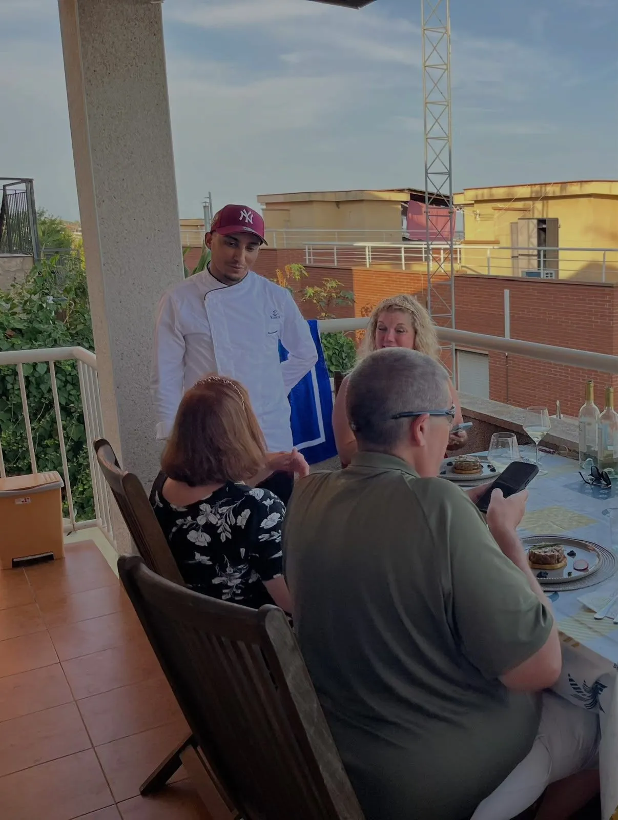 Moneim conversando con los invitados de una cena privada en una terraza