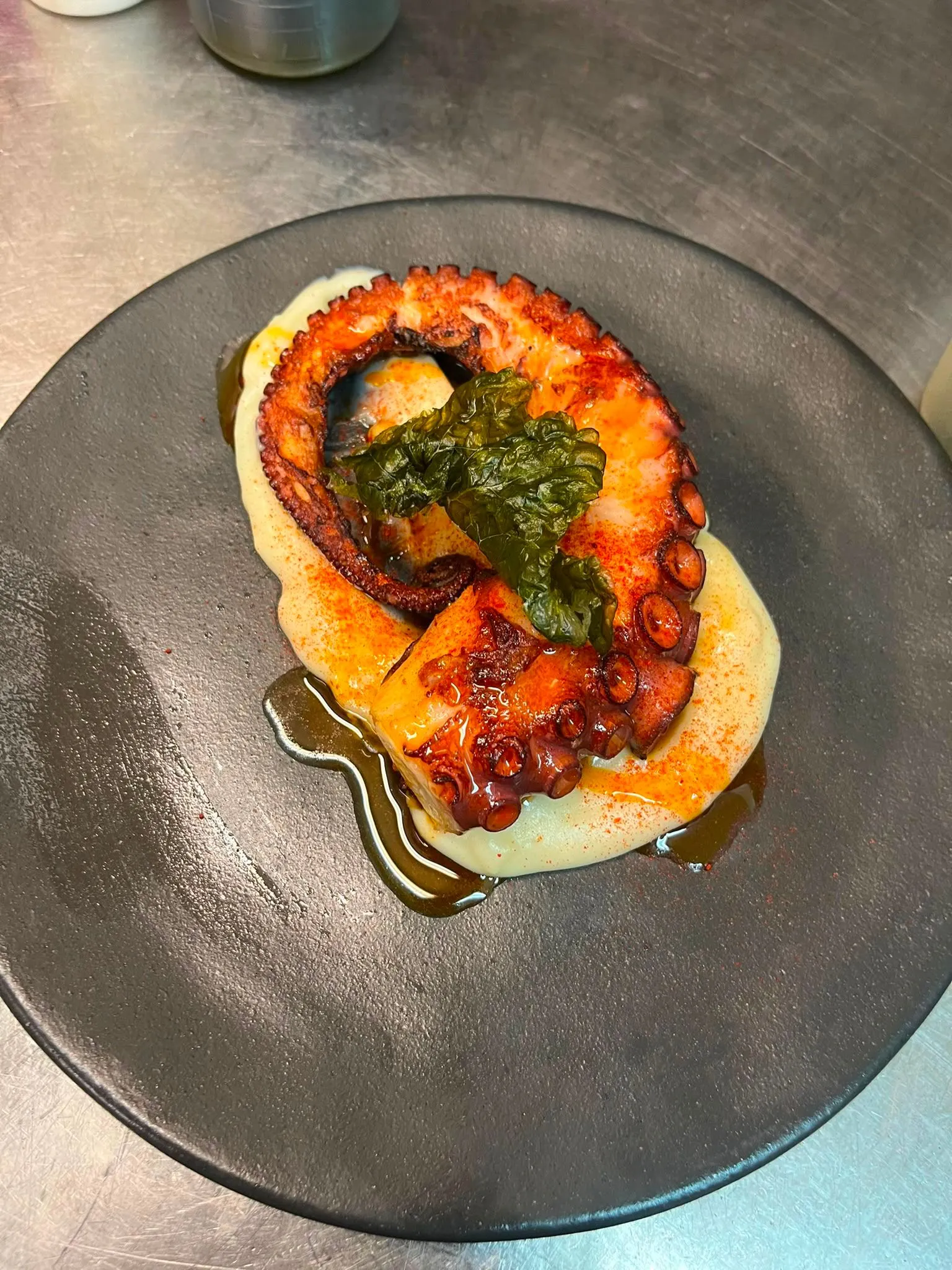 Pulpo a la brasa sobre crema de patata en plato negro
